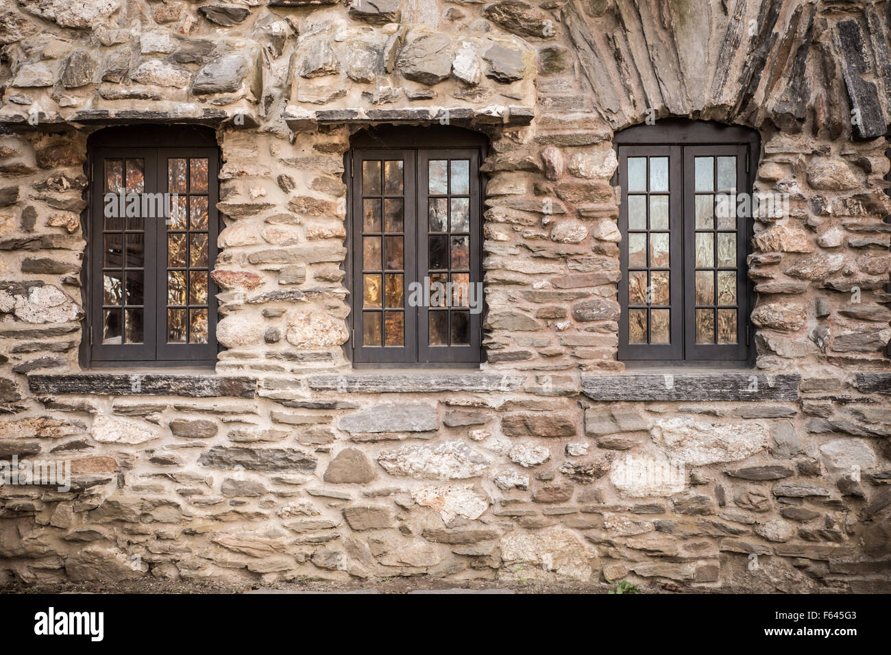 Mur de château en pierre extérieur avec trois fenêtres en verre Banque D'Images