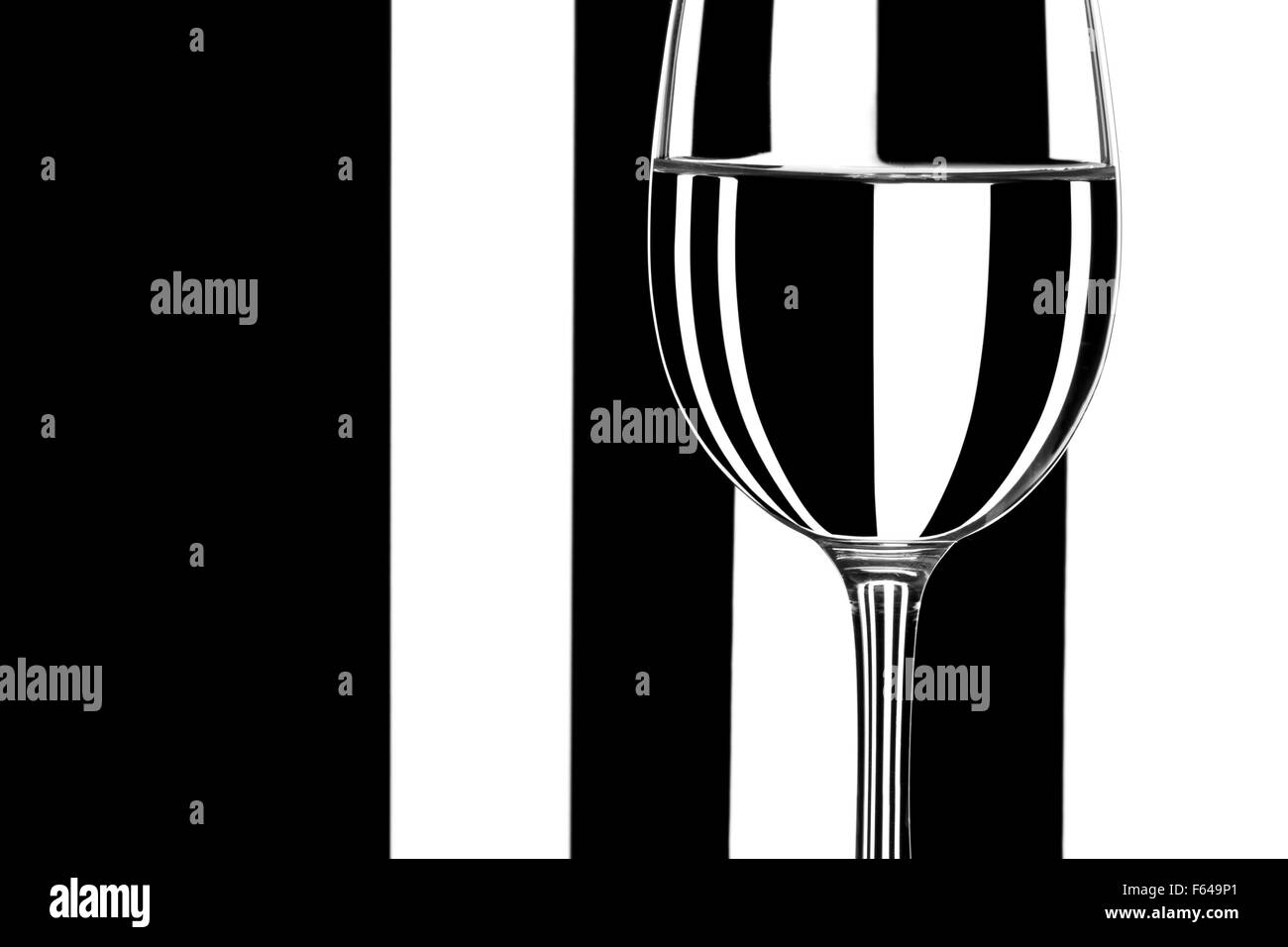 Verre d'eau contre l'arrière-plan noir et blanc à rayures Banque D'Images