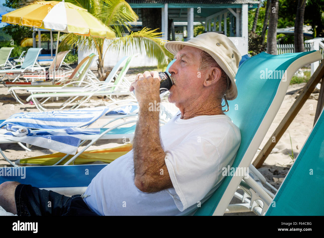 Un 77 ans caucasien homme boit un verre et vous détendre sur la plage de Sainte Croix, Îles Vierges des États-Unis. Banque D'Images