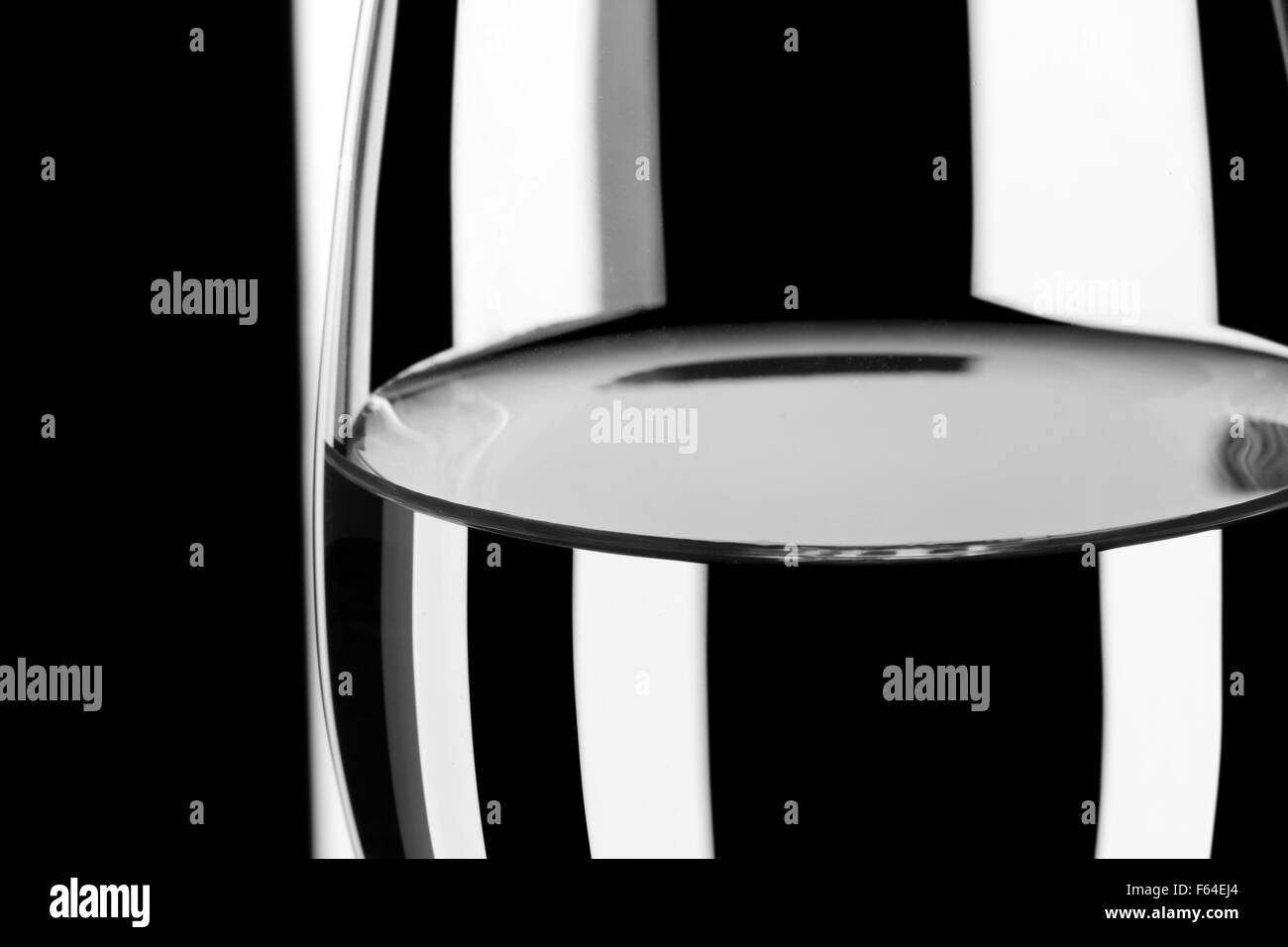 Verre d'eau contre l'arrière-plan noir et blanc à rayures Banque D'Images