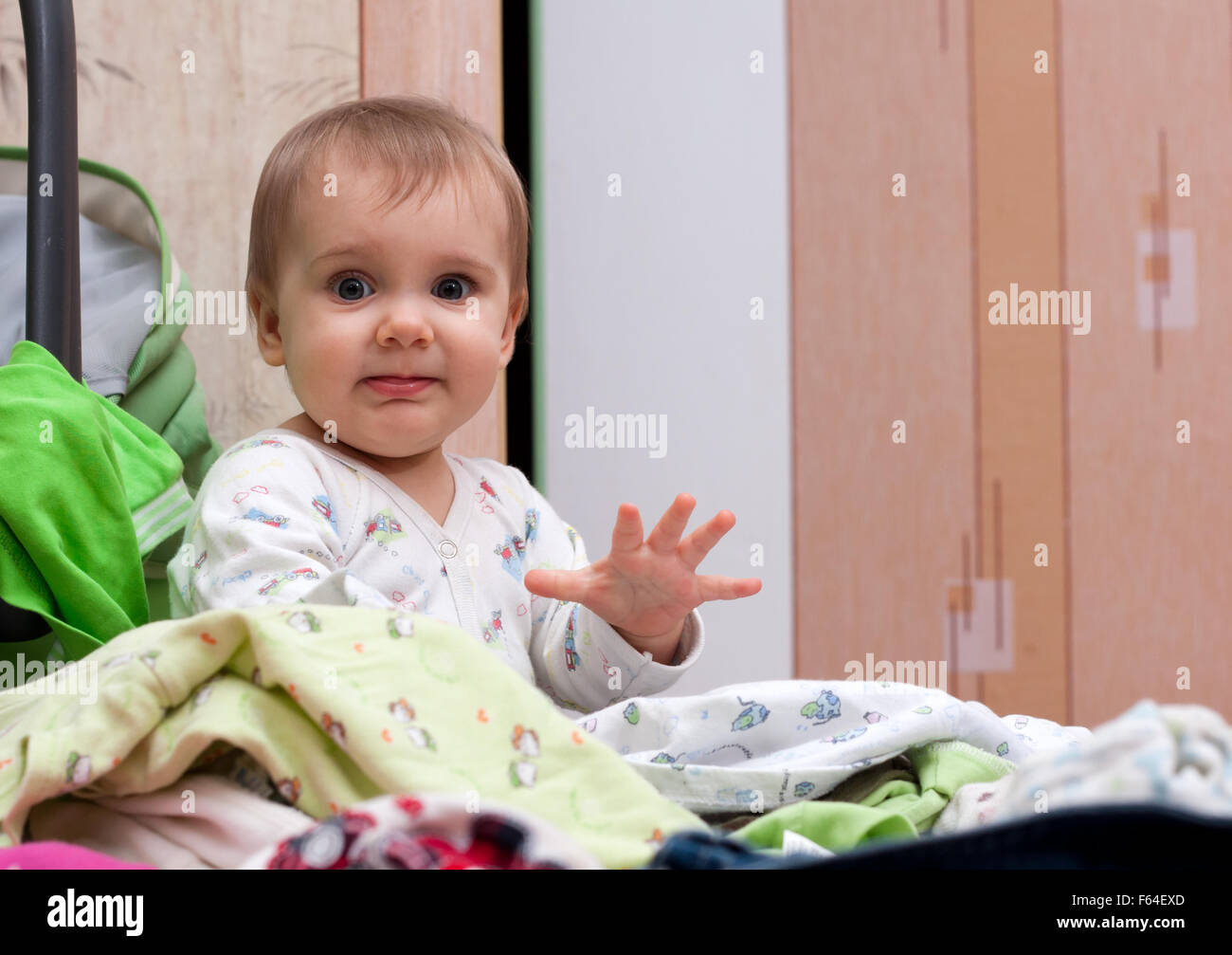 Happy baby girl playing in tas de vêtements pour bébé. Isolé Banque D'Images