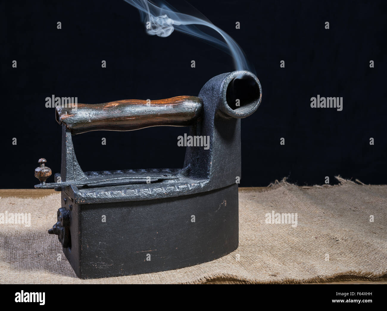 Fer à repasser chaud charbon rétro avec de la fumée sur table en bois Banque D'Images