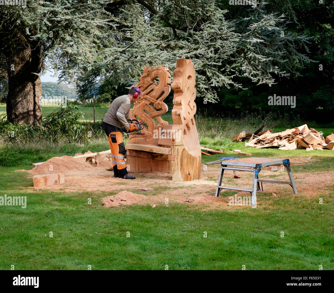 Une tronçonneuse sculpteur la création d'un jardin à thème dragon sculpture chaise à partir d'un tronc d'arbre au Cranborne Chase Woodfair, Wiltshire Banque D'Images