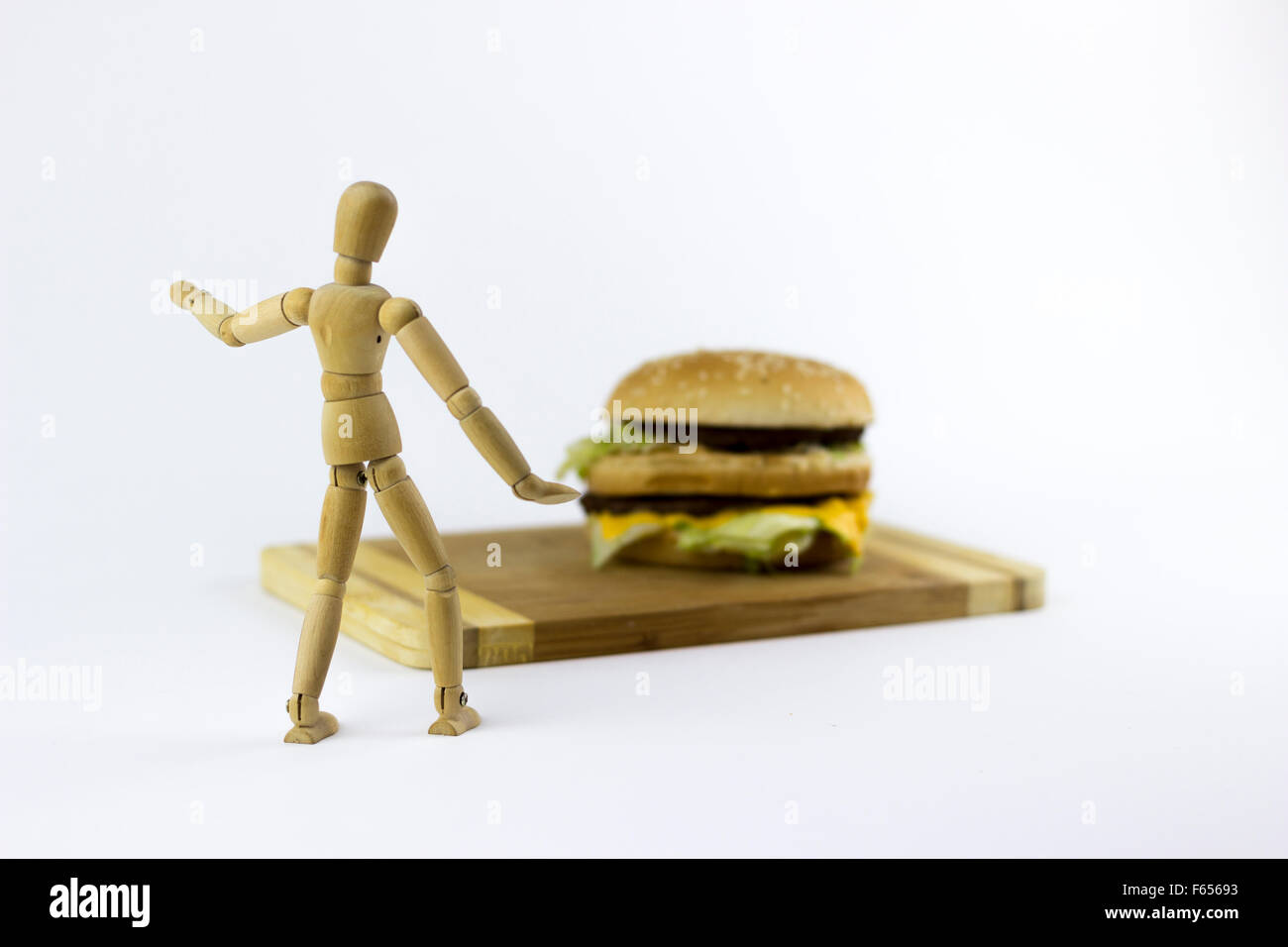 Une marionnette en bois à la recherche à un hambuger sur fond blanc Banque D'Images