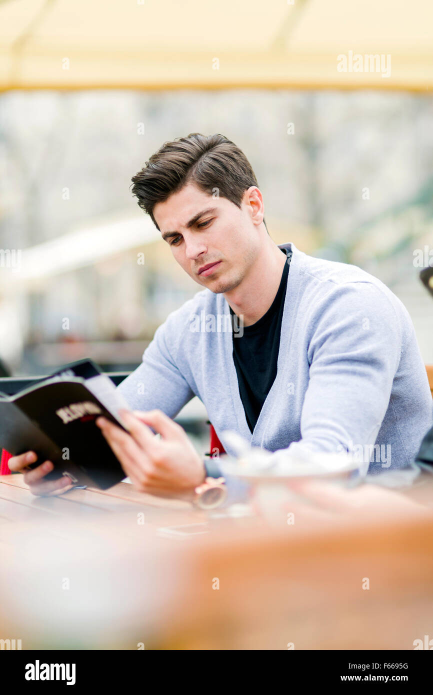 Beau jeune homme à la recherche, à l'aide du menu à l'extérieur Banque D'Images
