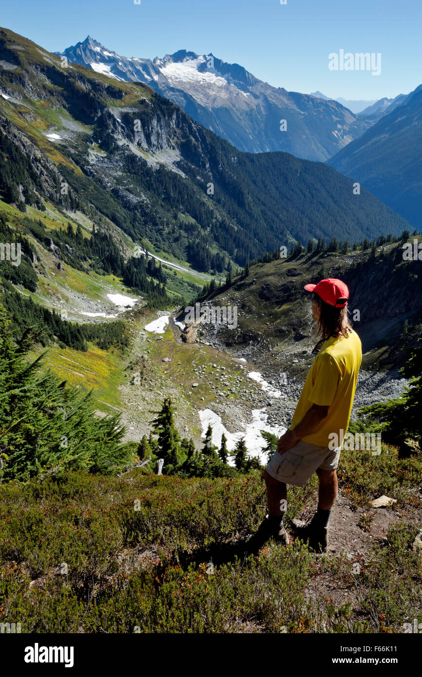 Randonneur à un col sans nom plus à la vallée du ruisseau du lac caché avec Boston et interdit au-delà des pics dans les North Cascades. Banque D'Images