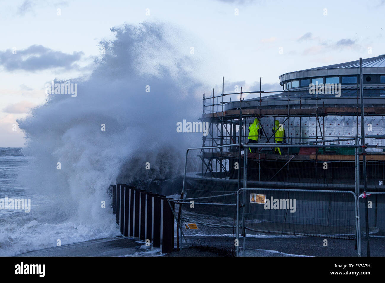 Aberystwyth, Pays de Galles, Royaume-Uni. 13 novembre 2015. Abigail lashes out tempête à Aberystwyth ce matin avec furious vagues tandis que deux constructeurs d'essayer de travailler sur l'échafaudage du nouveau kiosque sur la promenade. Crédit : Ian Jones/Alamy Live News Banque D'Images