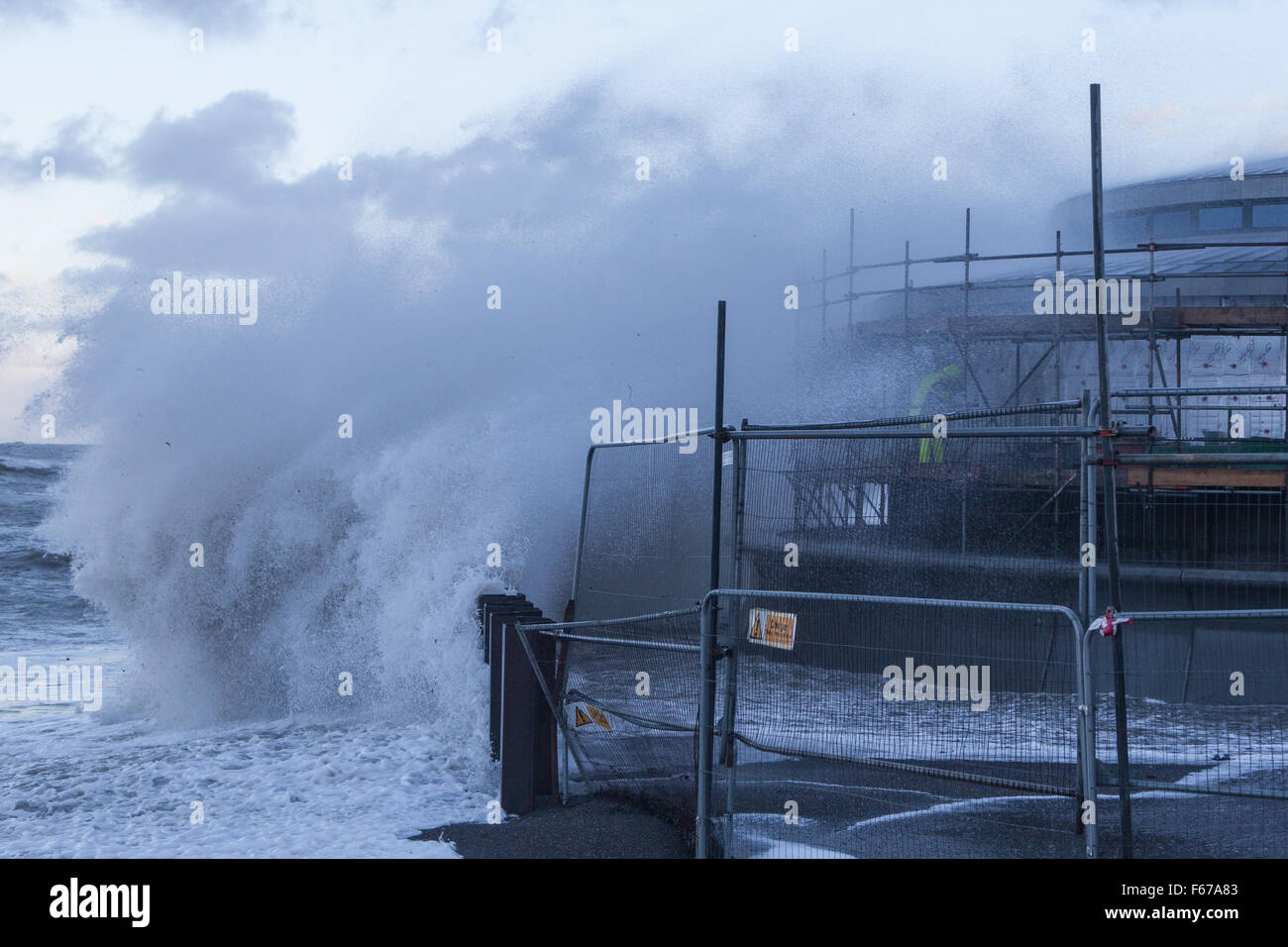 Aberystwyth, Pays de Galles, Royaume-Uni. 13 novembre 2015. Abigail lashes out tempête à Aberystwyth ce matin avec furious vagues tandis que deux constructeurs d'essayer de travailler sur l'échafaudage du nouveau kiosque sur la promenade. Crédit : Ian Jones/Alamy Live News Banque D'Images