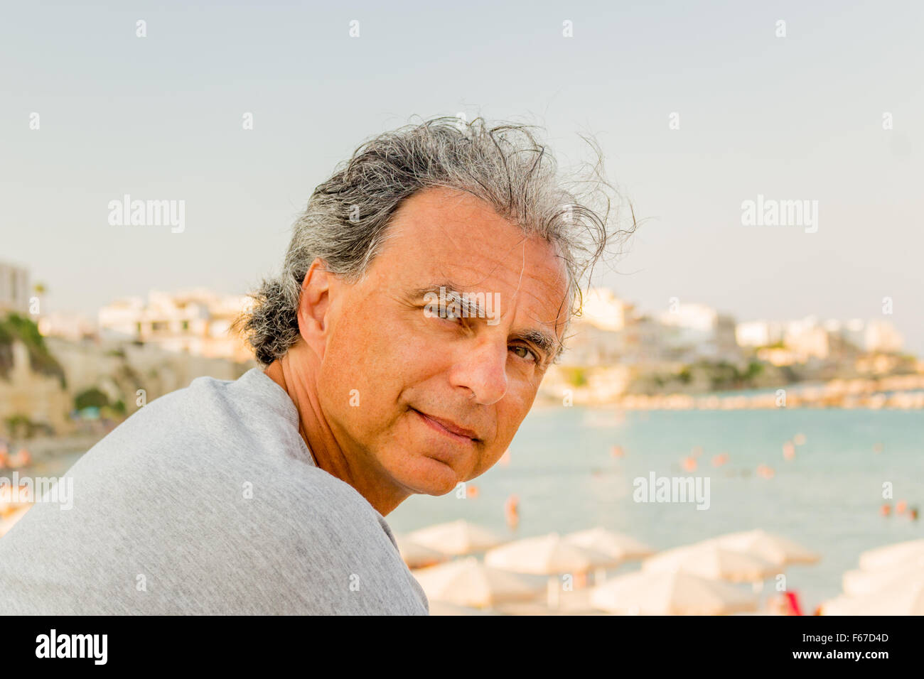 Souriant et bronzé middle-aged man détente en vacances, devant le magnifique panorama d'une ville côtière italienne Banque D'Images