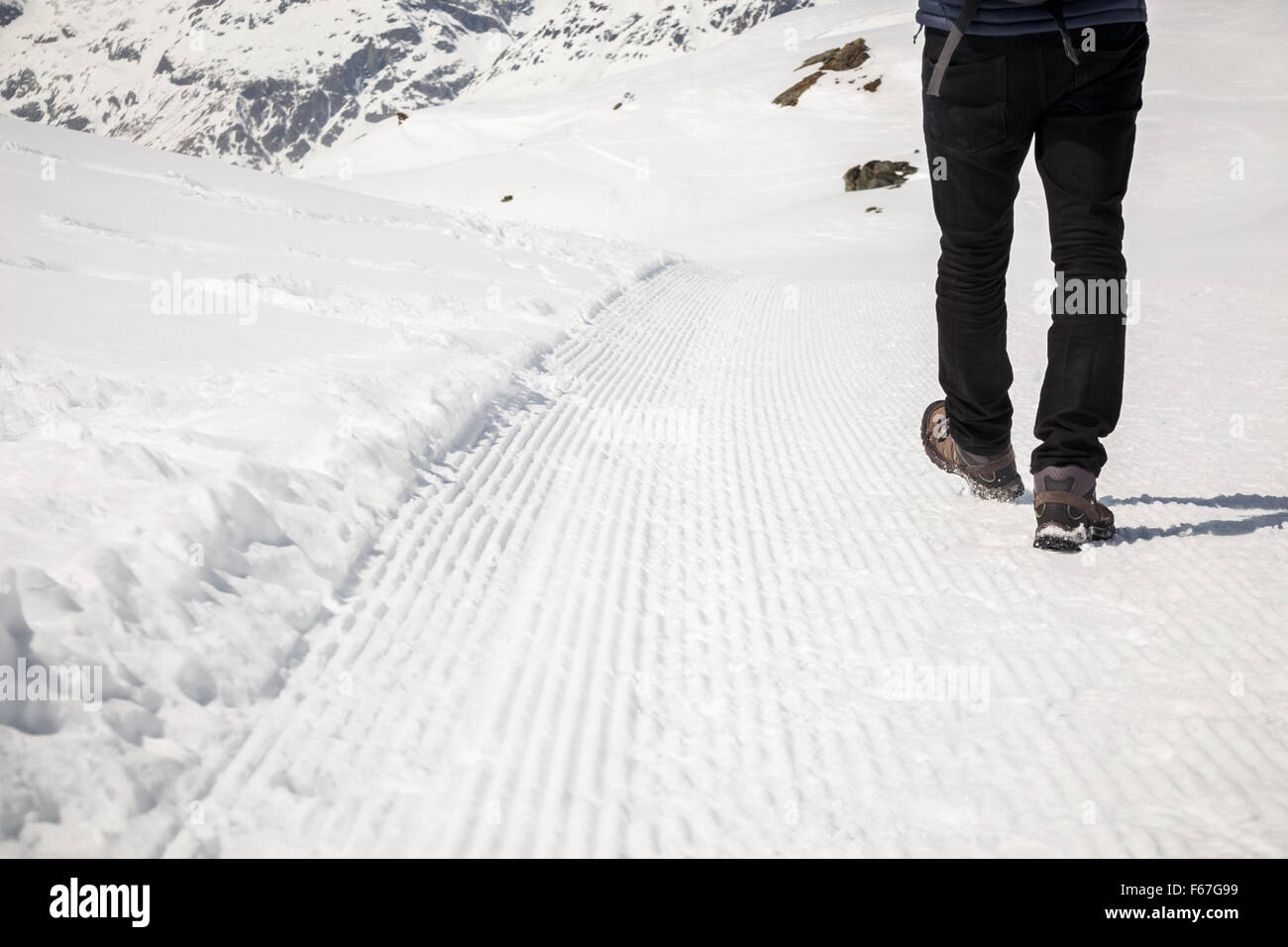 L'homme en noir marche sur le sentier de neige. Banque D'Images