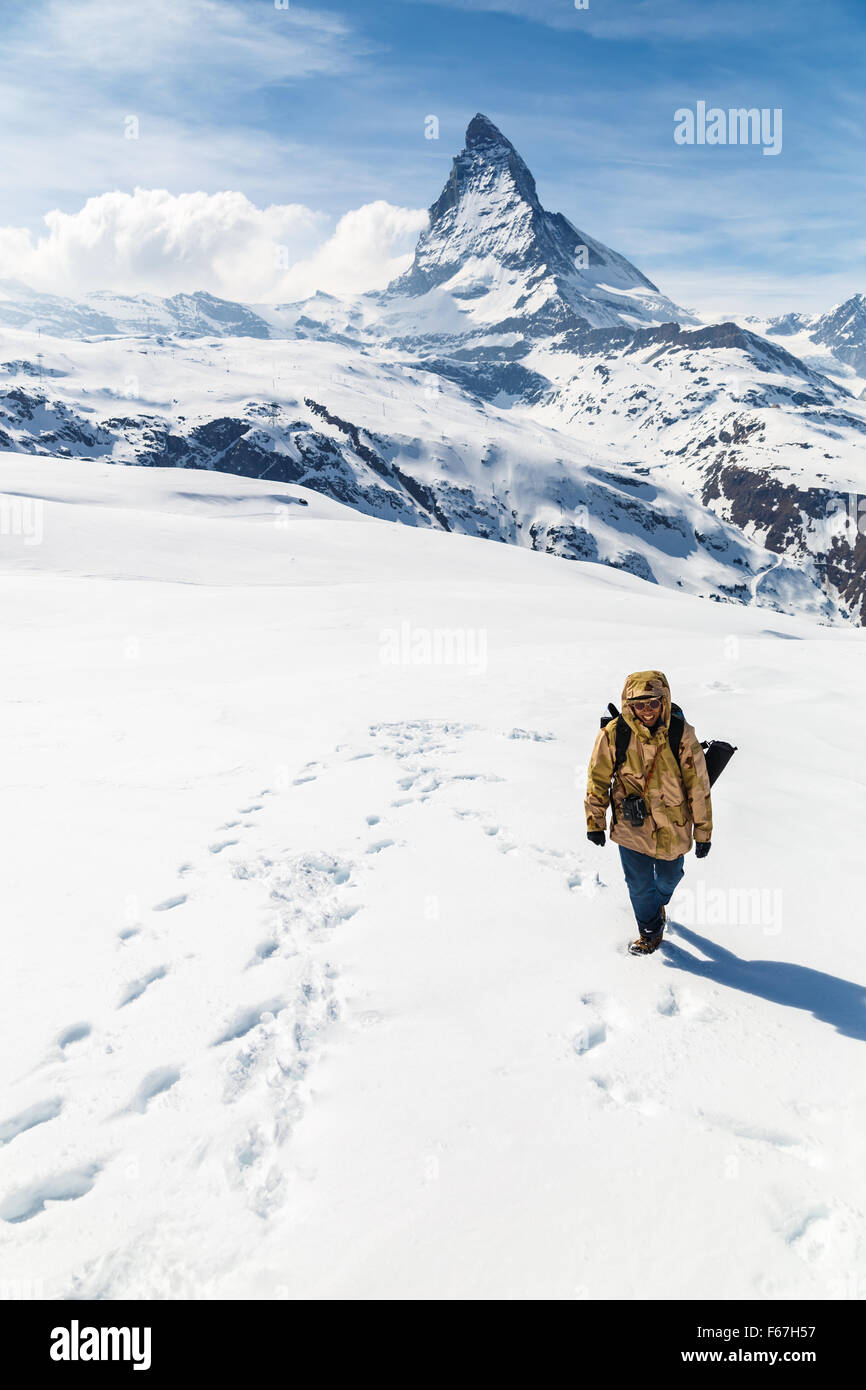 Un homme en manteau d'hiver camouflage marche sur la neige avec l'arrière-plan de Cervin. Banque D'Images