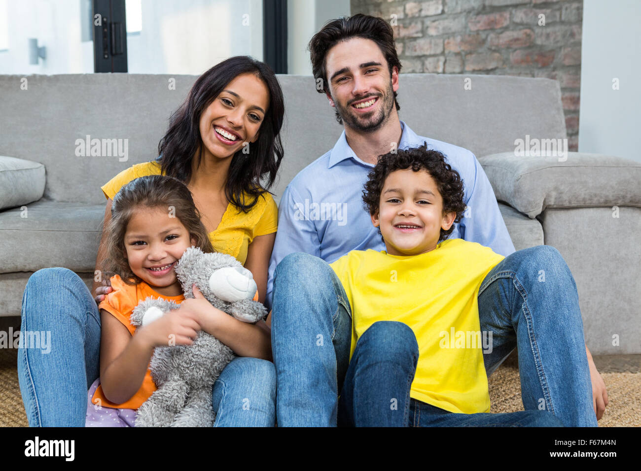 Smiling family assis sur un tapis dans la salle de séjour Banque D'Images