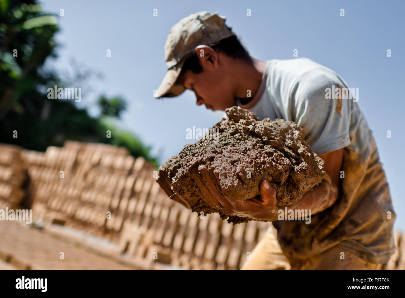 Moisés, une à l'âge de 13 ans, garçon salvadorien, transporte les matières de l'argile pour la fabrication de briques à une briqueterie dans Istahua, El Salvador. Banque D'Images