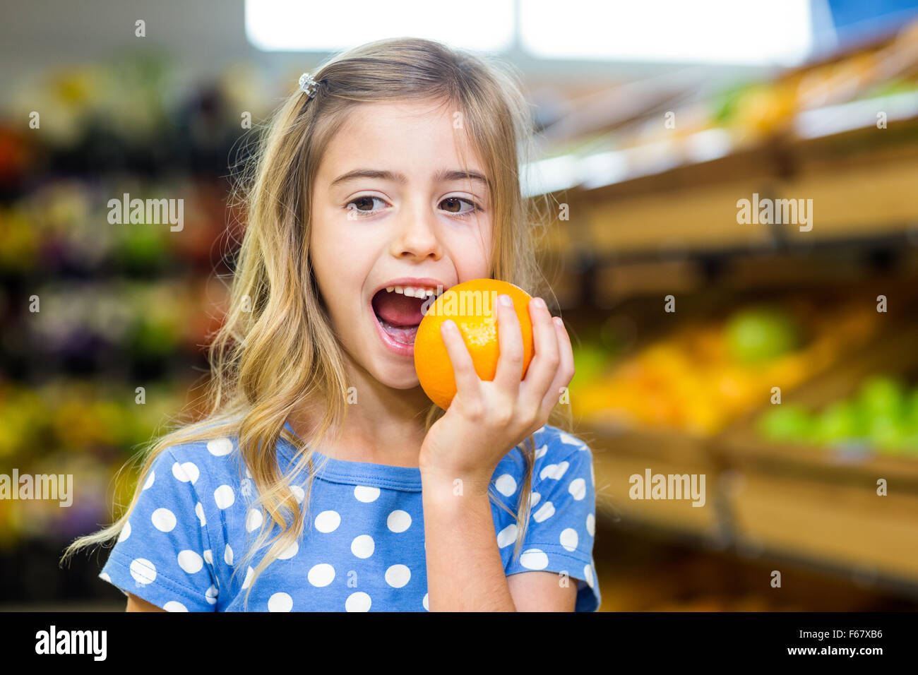 Smiling young girl eating une orange Banque D'Images
