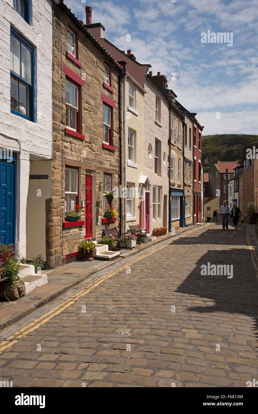 Les visiteurs de l'été vous promener jusqu'au soleil, étroites et pavées, High Street, dans le pittoresque village traditionnel de pêcheurs de Staithes, North Yorkshire, UK. Banque D'Images