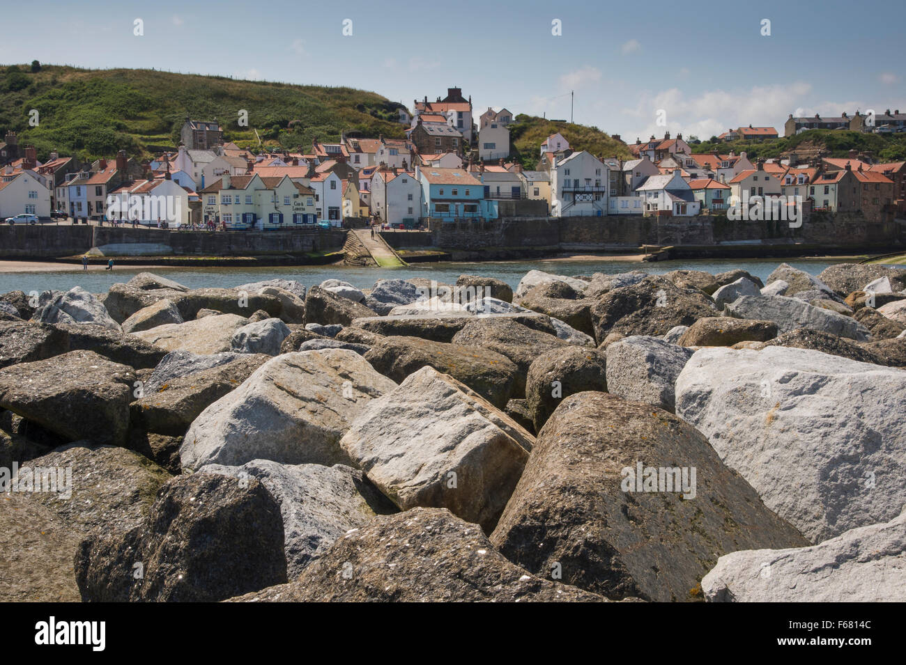 Vue d'été ensoleillé de village pittoresque de Staithes, North Yorkshire, UK, vus de derrière, les défenses de la mer (rochers) barrière de protection du port. Banque D'Images