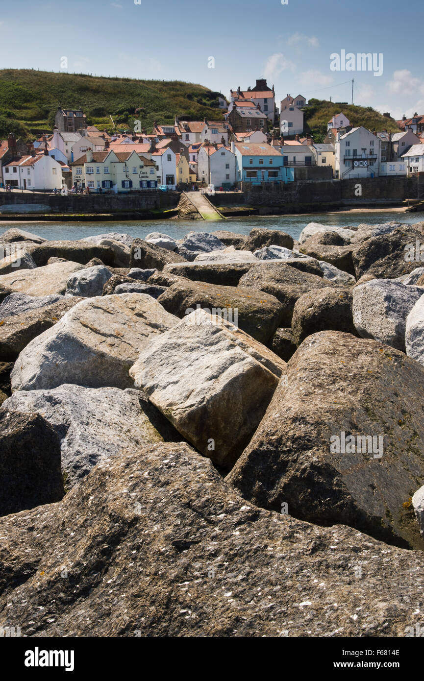 Vue d'été ensoleillé de village pittoresque de Staithes, North Yorkshire, UK, vus de derrière, les défenses de la mer (rochers) barrière de protection du port. Banque D'Images