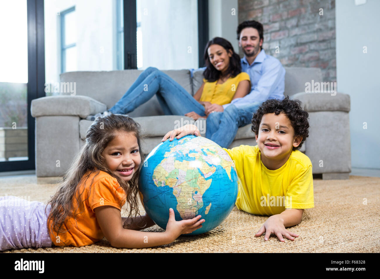Enfants holding globe sur la moquette dans la salle de séjour Banque D'Images