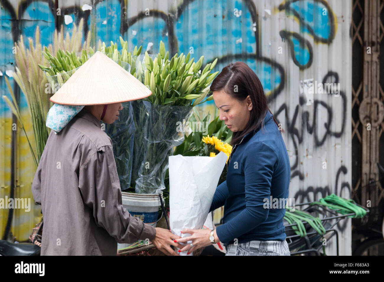 Dame vietnamienne vente de fleurs de son vélo dans vieux quartier de Hanoi, Vietnam Banque D'Images