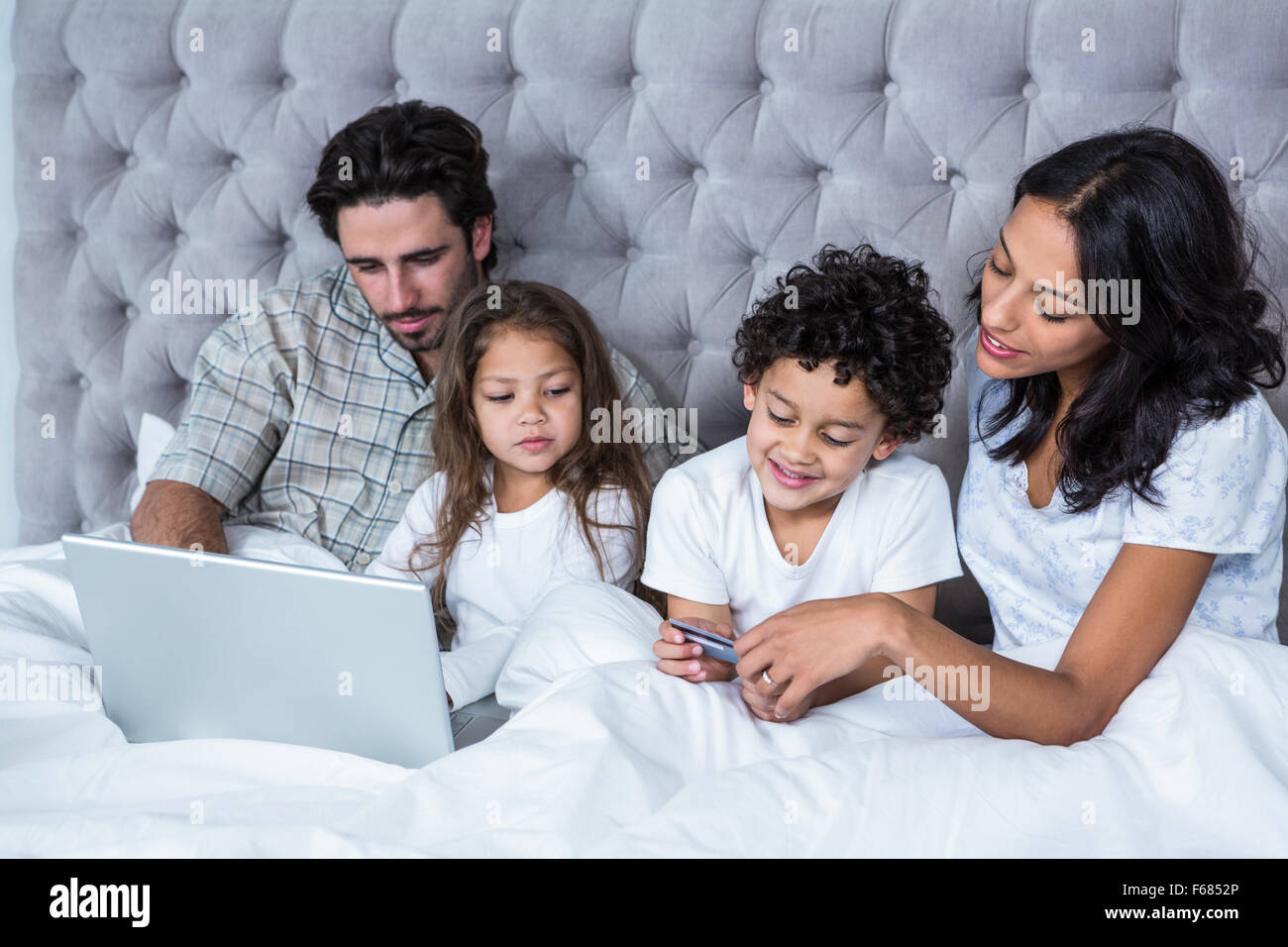Famille heureuse au lit des achats en ligne Banque D'Images