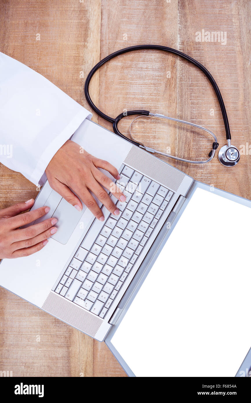 Médecin à l'aide d'un ordinateur portable sur un bureau en bois Banque D'Images