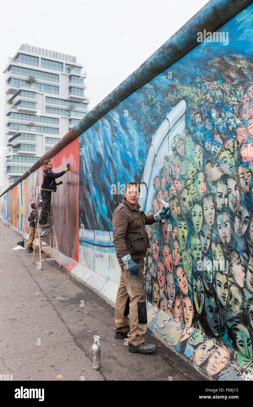 BERLIN, ALLEMAGNE - 30 octobre 2015 : Un homme nettoie une murale graffiti off à l'East Side Gallery. L'œuvre, "c'est arrivé en N Banque D'Images