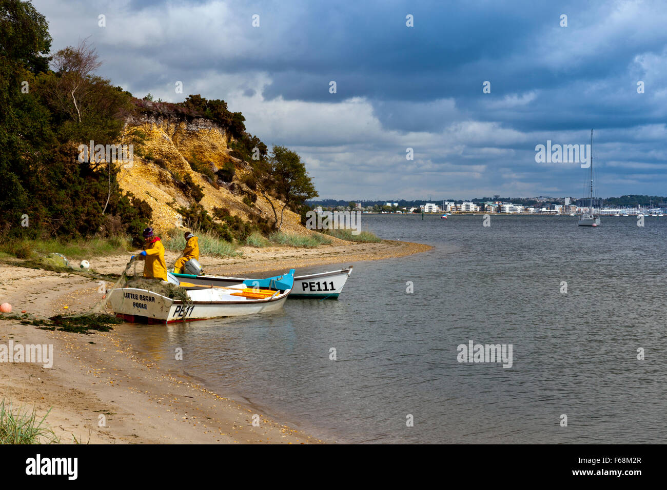 Bague deux pêcheurs net sur une plage de la RSPB Arne réserver dans le port de Poole, Dorset, Angleterre. Banque D'Images