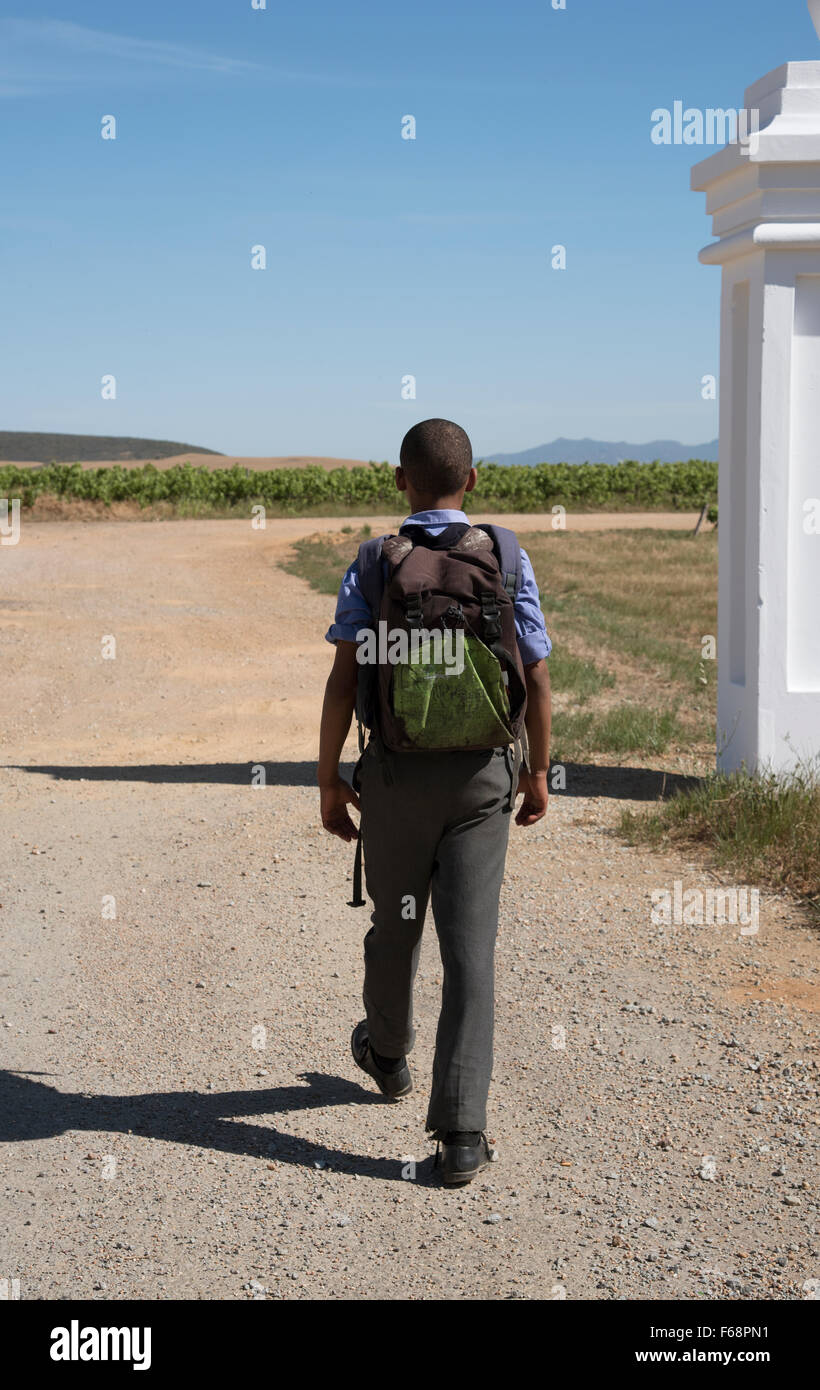 Un sac à dos de transport écolier à l'école à pied le long d'un chemin de terre d'Afrique Banque D'Images