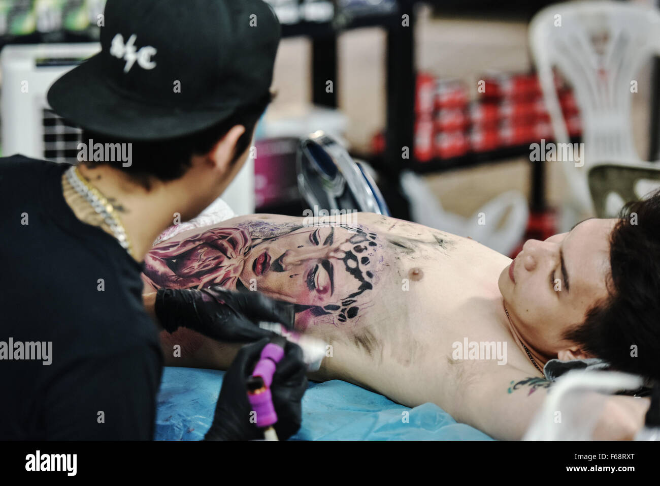 Bangkok, Thaïlande. 14Th Nov, 2015. Un tatoueur travaille sur un motif sur la poitrine d'un homme au cours de la MBK concours de tatouage à Bangkok, Thaïlande, le 14 novembre 2015. Des centaines de fans de tatouage à Bangkok le samedi pour le concours annuel de tatouage MBK, participant à des événements de style 16 y compris petit travail, old school, new school, réaliste et tribal. © Li Mangmang/Xinhua/Alamy Live News Banque D'Images