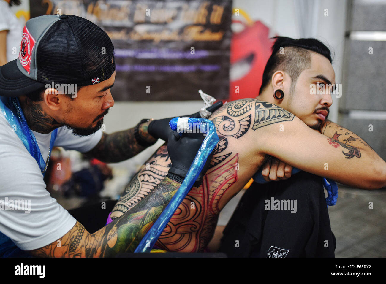 Bangkok, Thaïlande. 14Th Nov, 2015. Un tatoueur travaille sur un modèle sur un homme est de retour au cours de la MBK concours de tatouage à Bangkok, Thaïlande, le 14 novembre 2015. Des centaines de fans de tatouage à Bangkok le samedi pour le concours annuel de tatouage MBK, participant à des événements de style 16 y compris petit travail, old school, new school, réaliste et tribal. © Li Mangmang/Xinhua/Alamy Live News Banque D'Images Bangkok, Thaïlande. 14Th Nov, 2015. Un tatoueur travaille sur un modèle sur un homme est de retour au cours de la MBK concours de tatouage à Bangkok, Thaïlande, le 14 novembre 2015. Des centaines de fans de tatouage à Bangkok le samedi pour le concours annuel de tatouage MBK, participant à des événements de style 16 y compris petit travail, old school, new school, réaliste et tribal. © Li Mangmang/Xinhua/Alamy Live News Banque D'Images