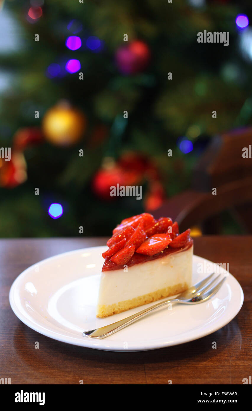 Gâteau au fromage aux fraises fraîches. Focus sélectif à l'avant du bord supérieur du gâteau. Arbre de Noël en arrière-plan Banque D'Images