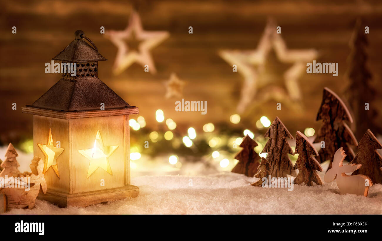 Arrangement de Noël confortable avec de beaux objets en bois sur la neige dans la chaude lumière des bougies d'une lanterne, nice studio discret sho Banque D'Images