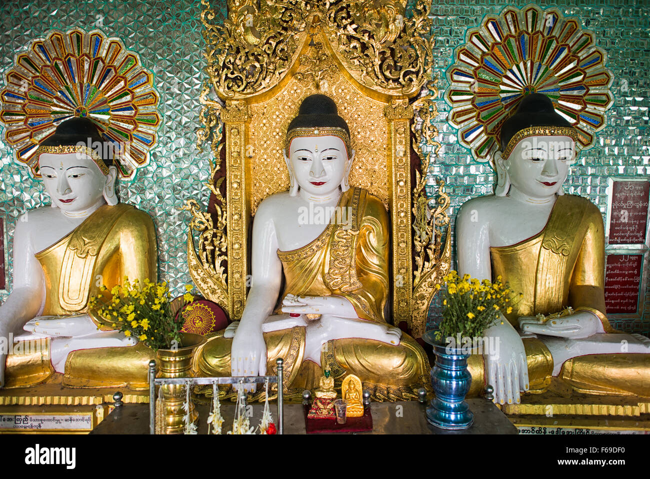 SAGAING, Myanmar — debout sur une colline à Sagaing, la pagode OoHminThoneSel présente une longue alcôve incurvée bordée de dizaines de statues du Bouddha. Après de récentes rénovations et améliorations en cours rendues possibles par des donateurs, la pagode est richement décorée avec des mosaïques de carreaux colorés et de la peinture fraîche et brillante. Banque D'Images