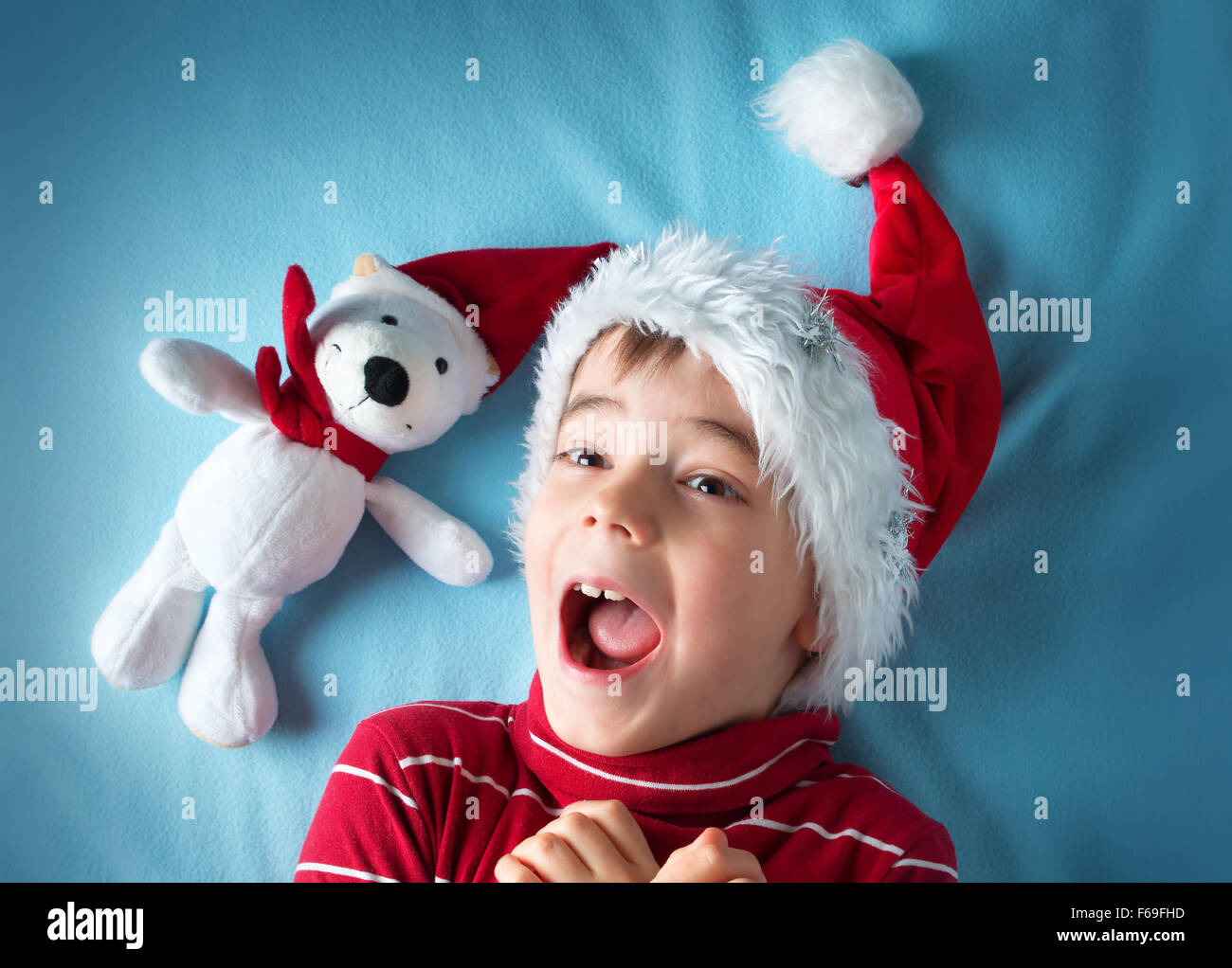 Happy boy à santa claus hat avec un ours blanc sur fond bleu Banque D'Images