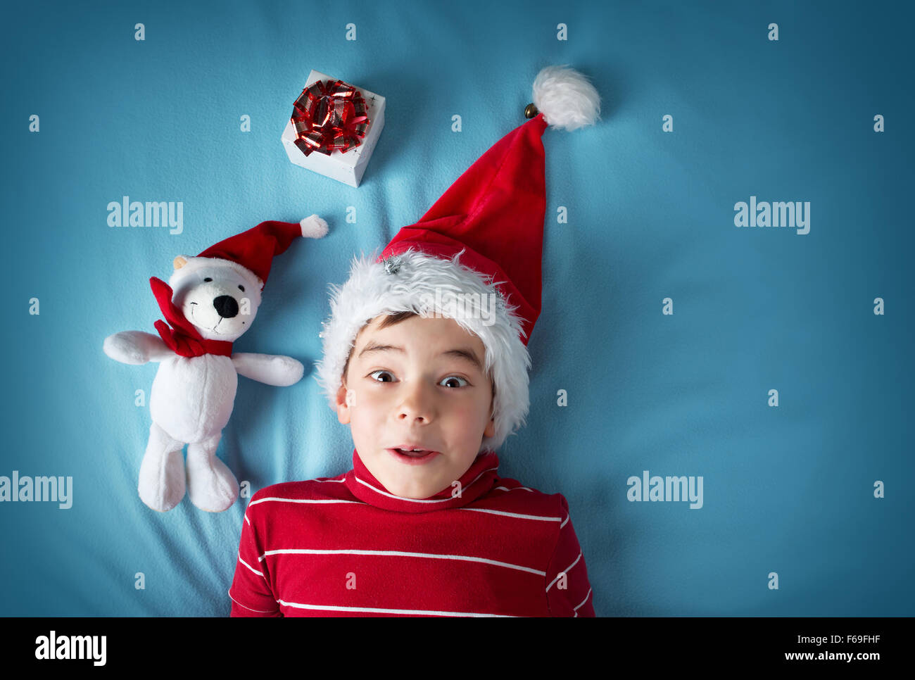 Happy boy à santa claus hat avec un ours blanc sur fond bleu Banque D'Images