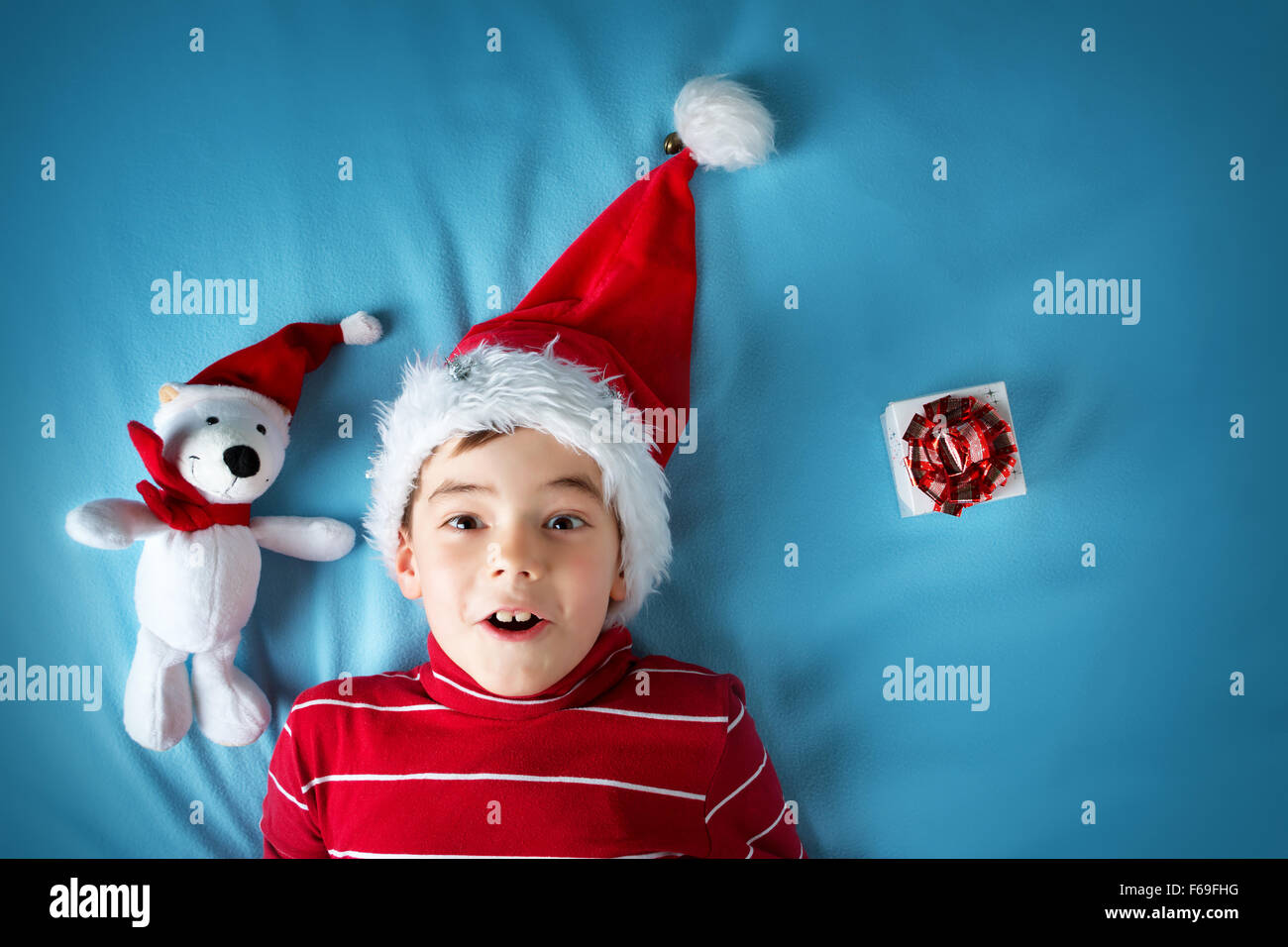 Happy boy à santa claus hat avec un ours blanc sur fond bleu Banque D'Images