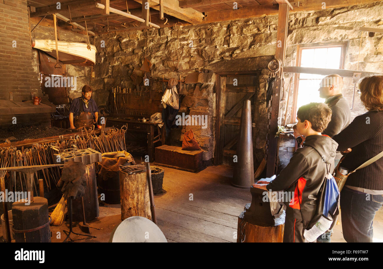 Les gens regardent une démonstration éducative par un forgeron dans les années 1800, l'Old Sturbridge Village, Massachusetts MA USA Banque D'Images