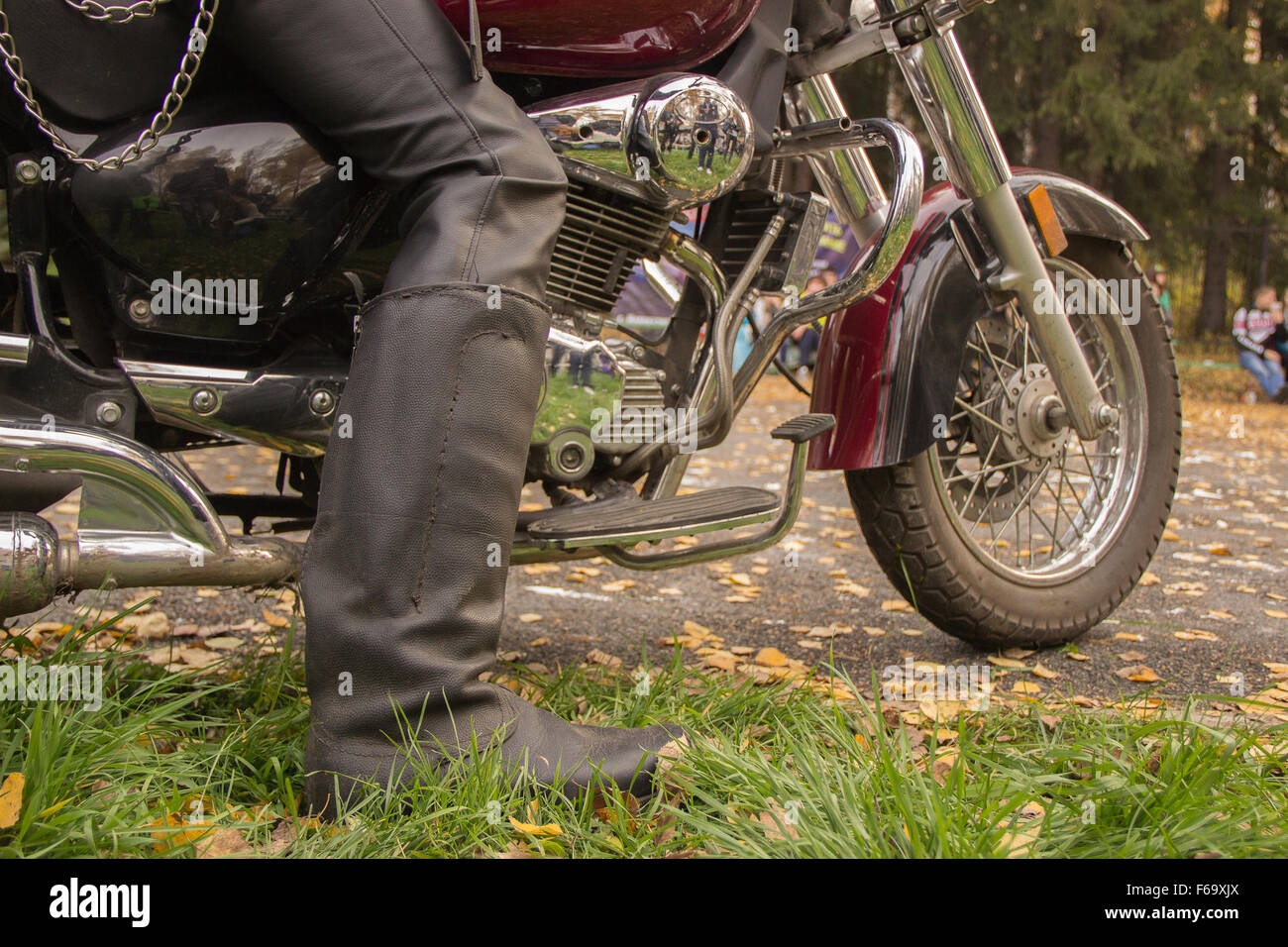 Biker dans des bottes noires assis sur une moto bourgogne Banque D'Images