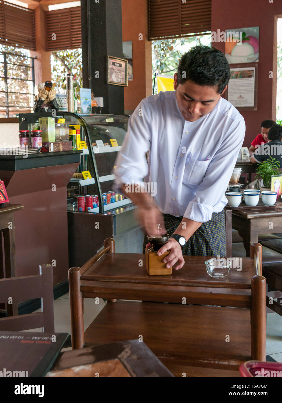 Serveur dans un café à Pyin Oo Lwin (Maymyo) au Myanmar la préparation du café fraîchement moulu. Les fèves sont d'abord la masse dans un broyeur. Banque D'Images
