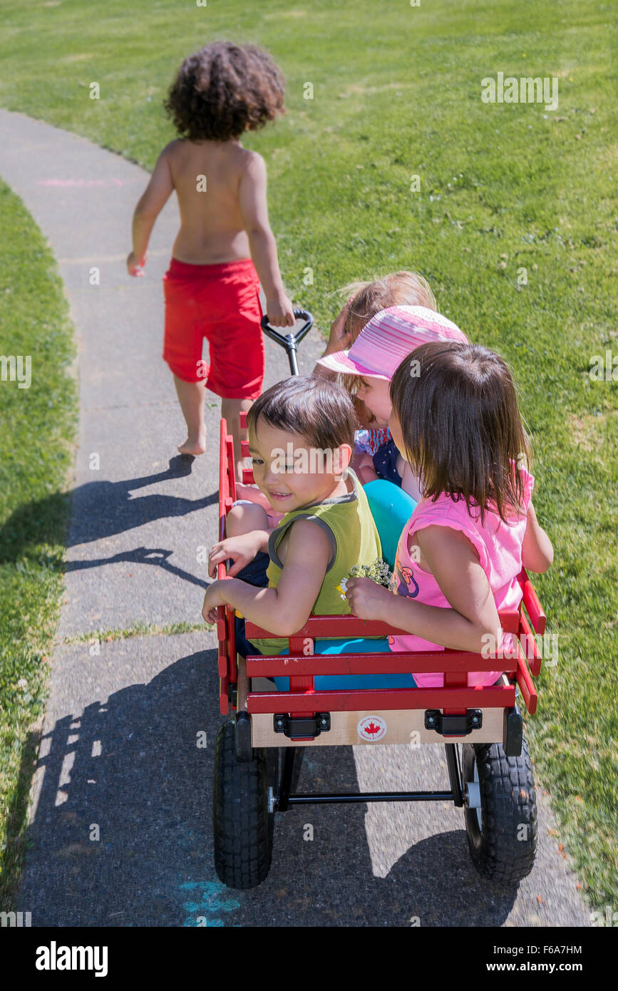 Garçon tirant d'autres enfants sur un chariot. Banque D'Images