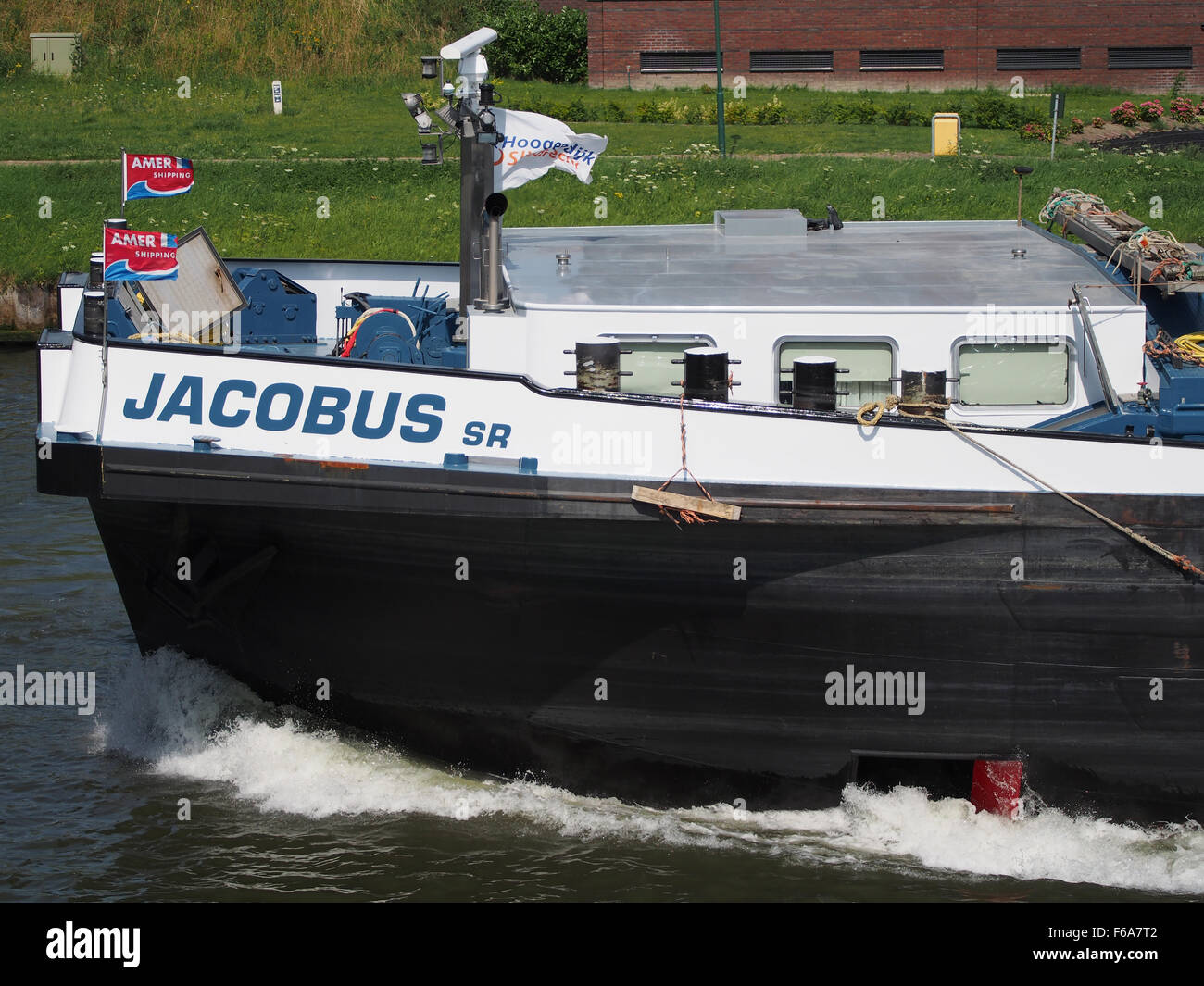 Cette photographie représente un porte-conteneurs naviguant sur le canal Amsterdam-Rijn, montrant les opérations logistiques et de transport impliquées dans le transport maritime, y compris le stockage, les grues et diverses marchandises transportées par mer. Banque D'Images