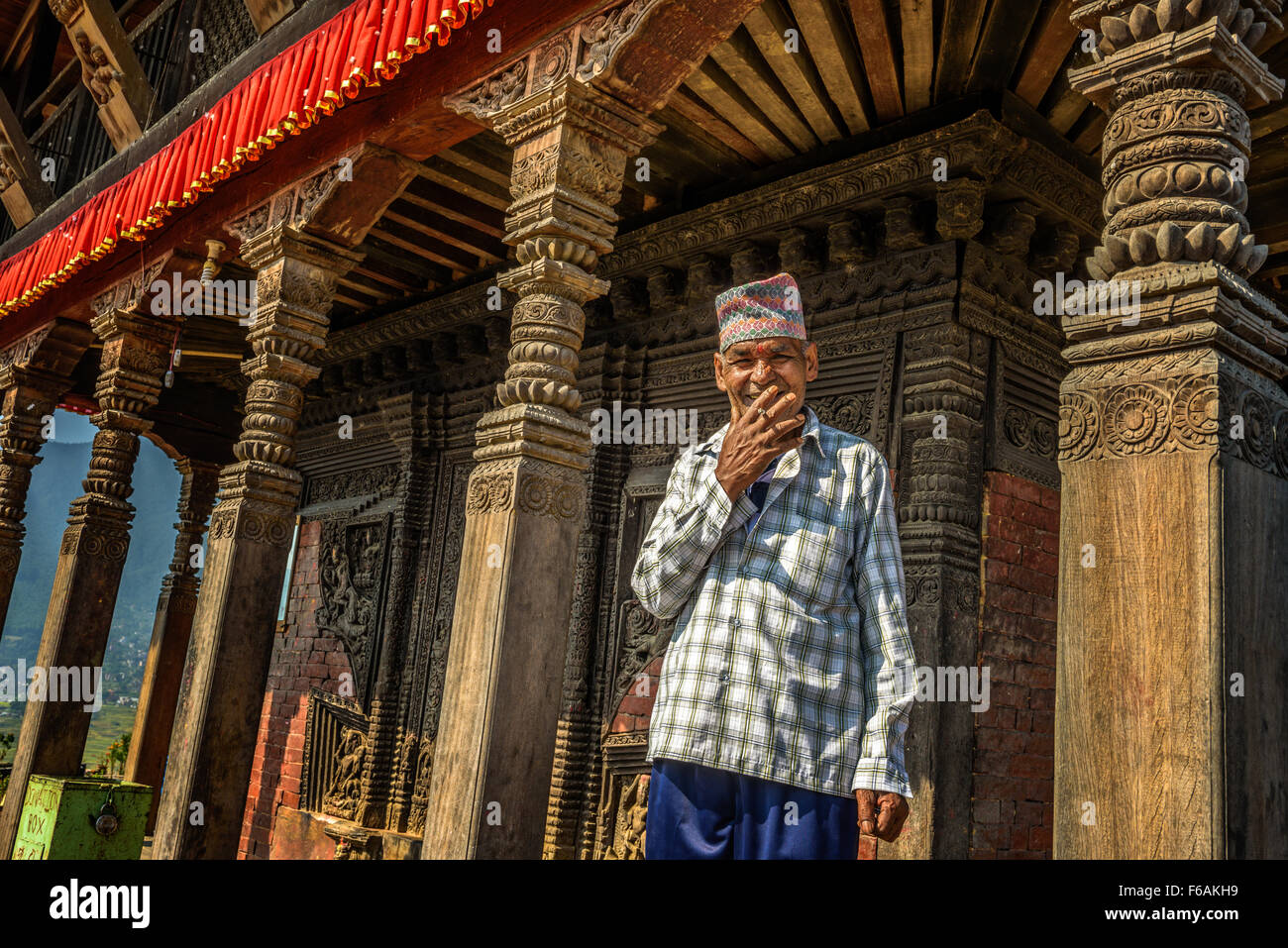 Ancien moine bouddhiste cigarette dans son temple à Katmandou Banque D'Images