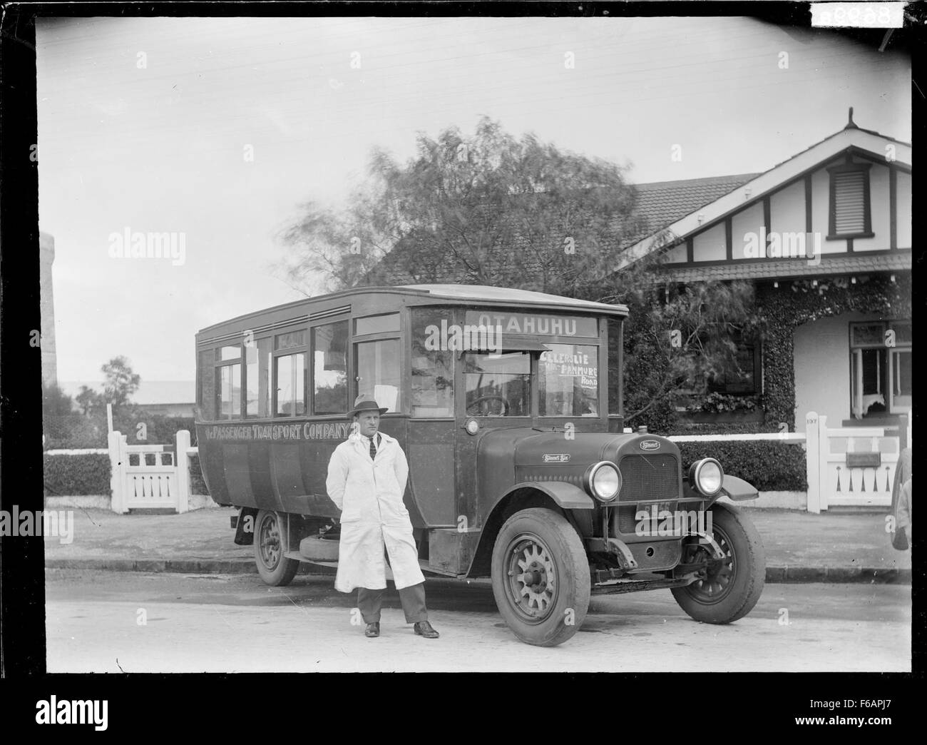 Cette photographie capture un bus et un chauffeur de la Passenger transport Company à Otahuhu, en Nouvelle-Zélande, offrant un aperçu des transports publics du milieu du XXe siècle. L’image met l’accent sur l’autobus comme élément central du système de transport en commun de la ville. Banque D'Images