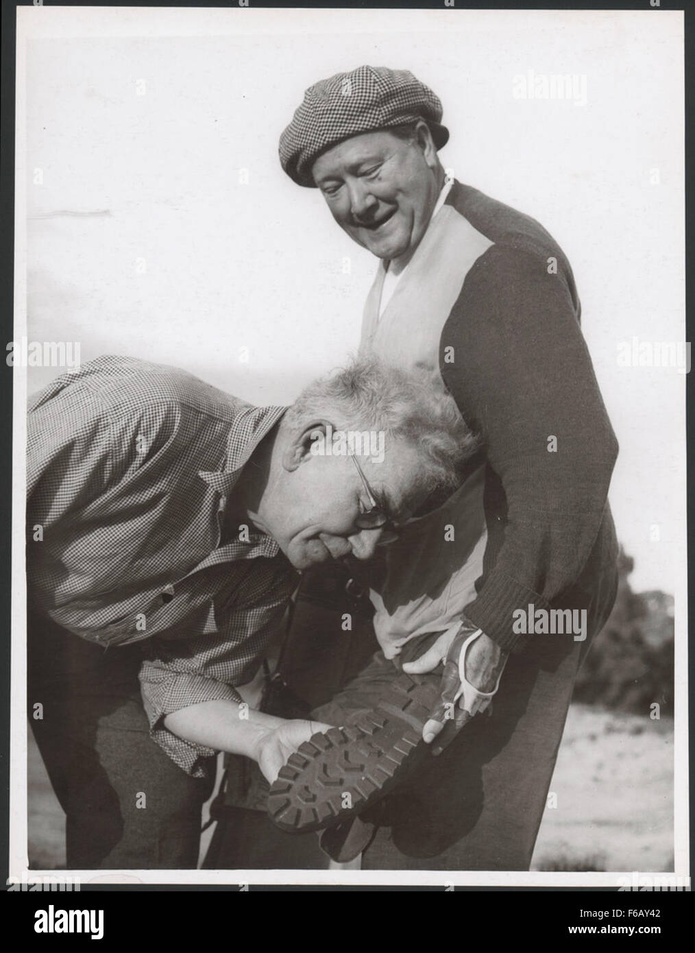 John Charles Thomas, un chanteur américain, est vu présenter ses chaussures de golf américaines à Mr. (nom peu clair), dans une interaction qui reflète son style personnel et ses intérêts au-delà de sa carrière de chanteur. Banque D'Images