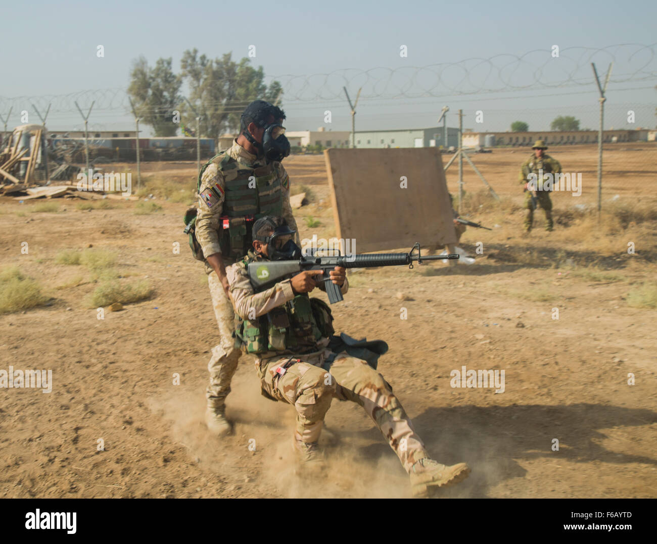 Un soldat irakien affecté à la 71e Brigade de l'armée iraquienne de dommages à couvrir les pratiques faisant glisser sous le feu au cours de l'exercice de patrouille au camp Taji, l'Iraq, le 15 octobre 2015. Des soldats iraquiens effectué des exercices de base tout en portant un masque de protection afin de simuler l'environnement créé par une vigoureuse attaque biochimique. La participation à ce type de formation au Camp Taji renforcer les capacités des partenaires site sera de préparer les soldats pour les attaques biochimiques potentiels lors du combat contre l'Etat islamique d'Irak et du Levant. (U.S. Photo de l'armée par la CPS. William Marlow/libérés) Banque D'Images