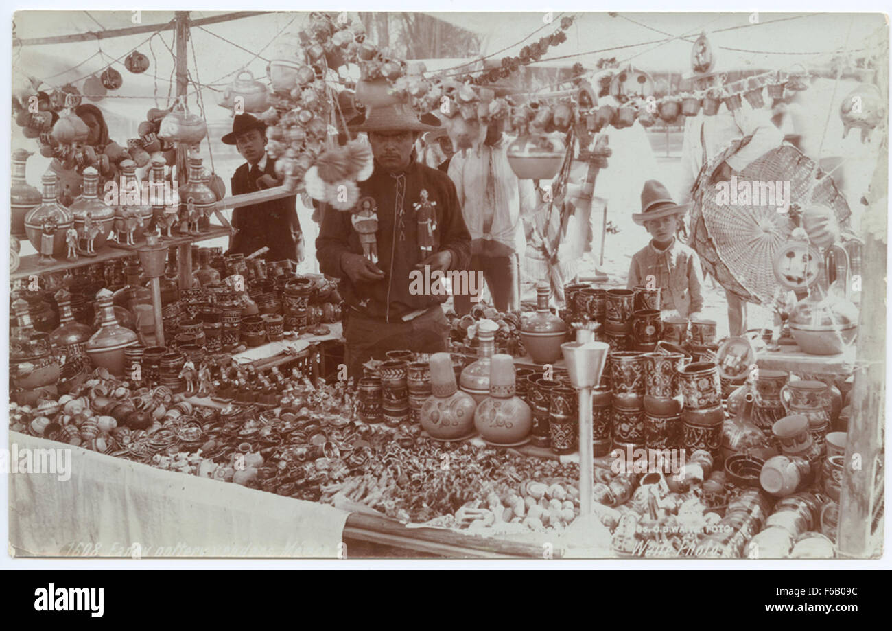 Photographie de vendeurs de poterie mexicains exposant des céramiques traditionnelles dans un cadre de marché dynamique. Banque D'Images