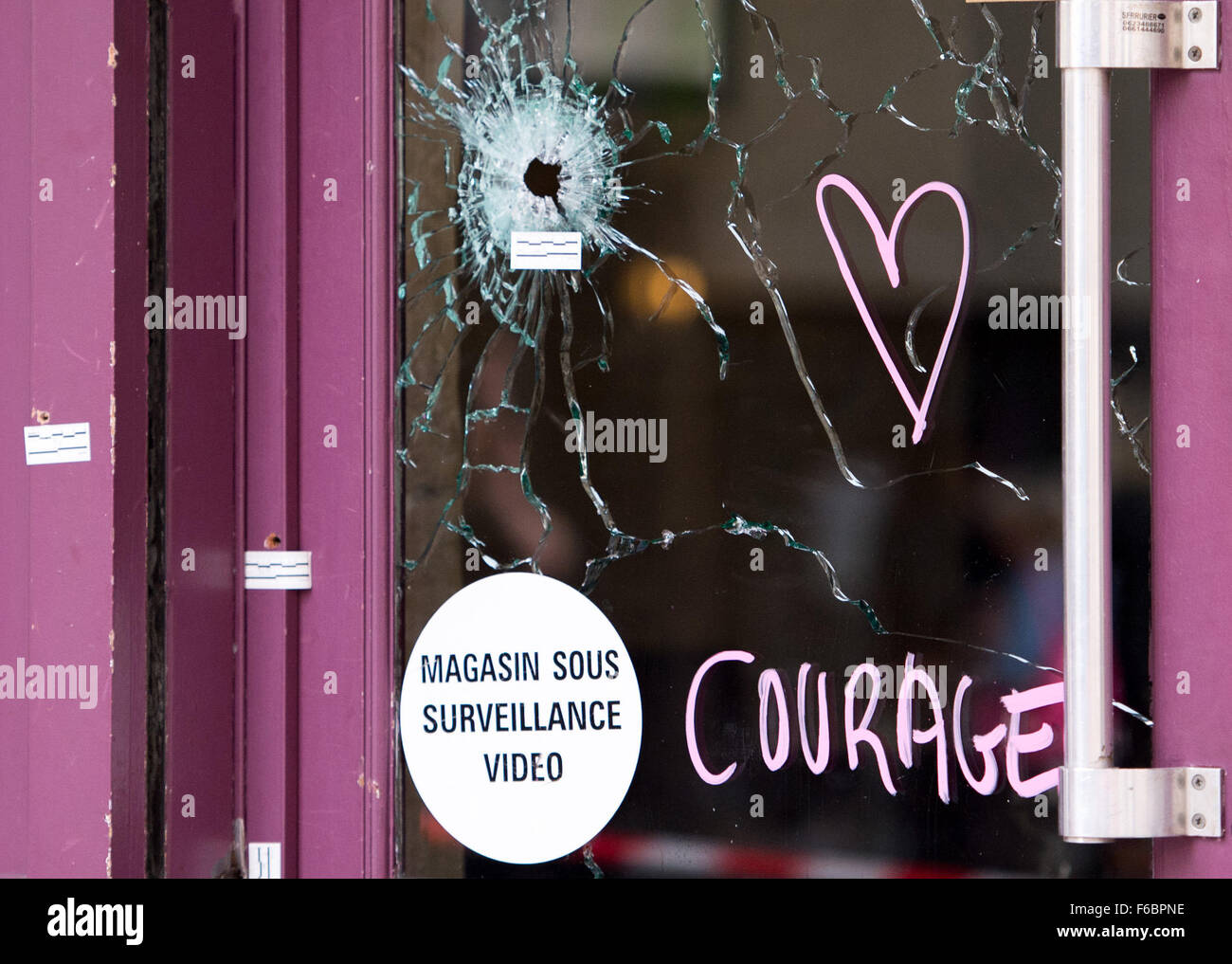 Paris, France. 16 Nov, 2015. Un coeur et le mot 'courage' ont été dessiné à côté de balles sur une glace au restaurant "Casa Nostra" près de la rue de la Fontaine au Roi à Paris, France, le 16 novembre 2015. Au moins 129 personnes ont été tuées au cours d'une série d'attaques de terreur nuit à Paris du 13 au 14 novembre 2015. Photo : MARIUS BECKER/dpa () prévisualisée/dpa/Alamy Live News Banque D'Images