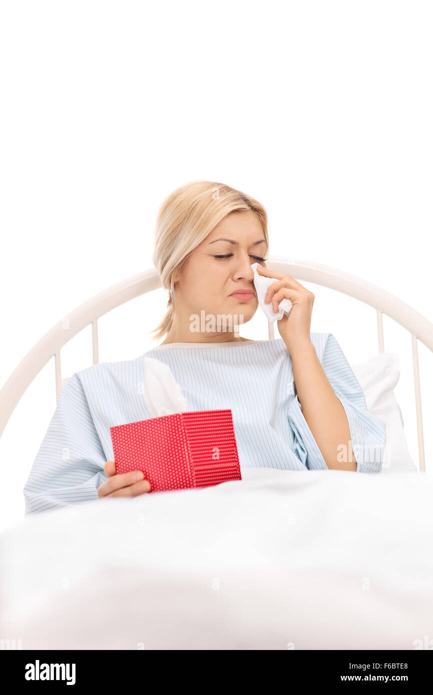 Shot verticale d'une triste femme patient allongé sur un lit d'hôpital et de pleurer isolé sur fond blanc Banque D'Images