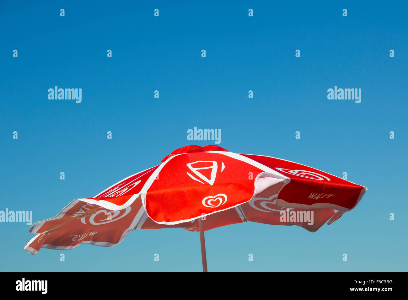 Le mur rouge de la crème glacée de marque ombrelle de table, dans le vent  contre un ciel bleu clair et lumineux Photo Stock - Alamy