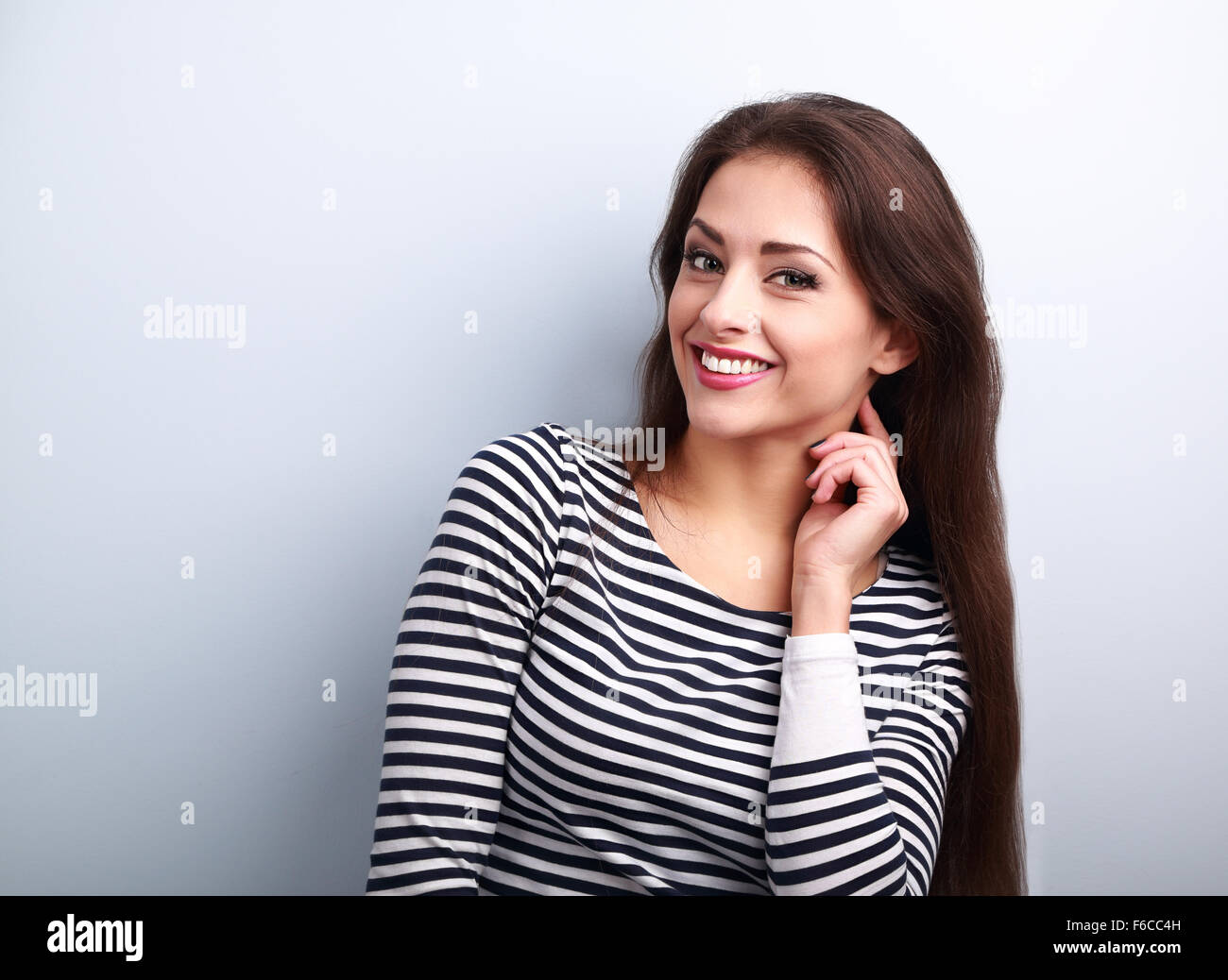 Happy smiling young casual femme aux cheveux longs à la recherche sur fond bleu Banque D'Images